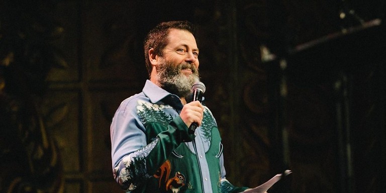 Nick Offerman on stage with microphone. Wearing western chain stitched shirt featuring squirrels.