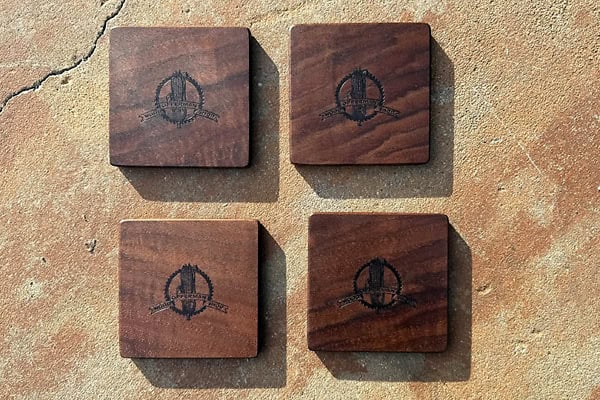 Handcrafted walnut coaster set with engraved logo for stylish protection.